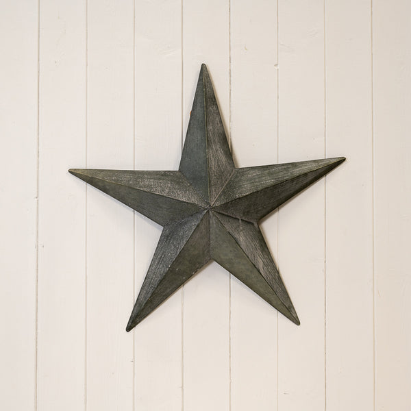 Natural grey metal star decoration displayed on a white panelled wall