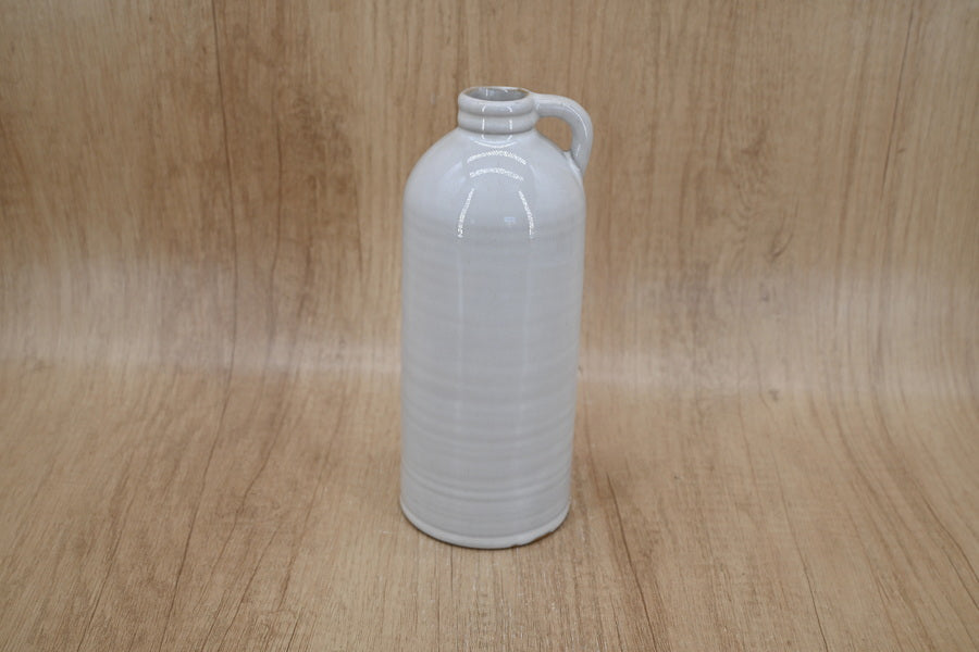 Tall white jug-shaped vase on a wood backdrop