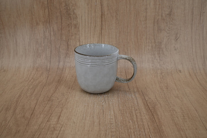 Pale grey ridged stoneware mug photographed against a wood-effect backdrop