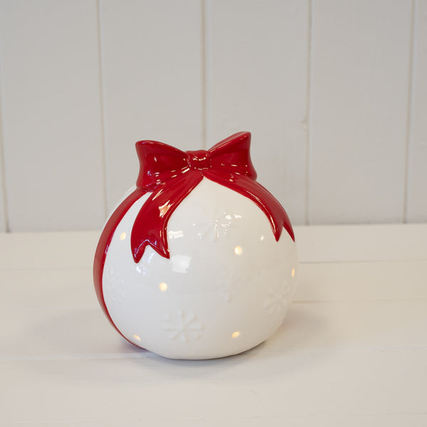 White Christmas bauble with red bow, shown illuminated