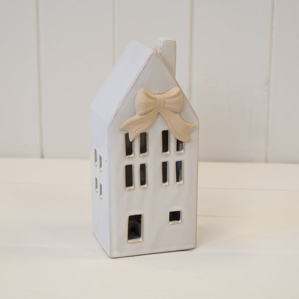 White ceramic house with a bow above its windows