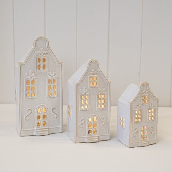 Three illuminated white Christmas townhouses in different sizes