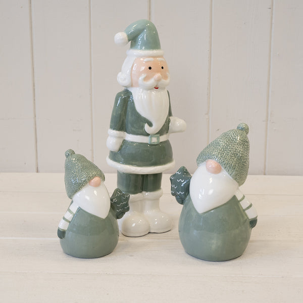 Green Santa ornament displayed with two smaller green figures