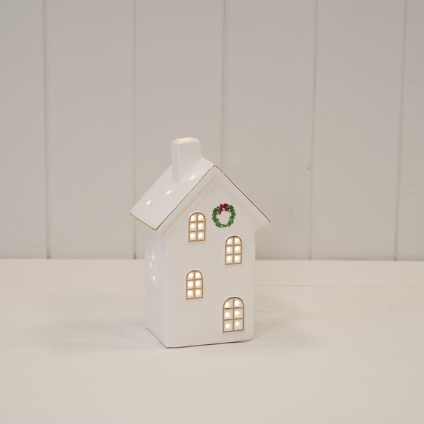Small white LED house with a wreath on its front