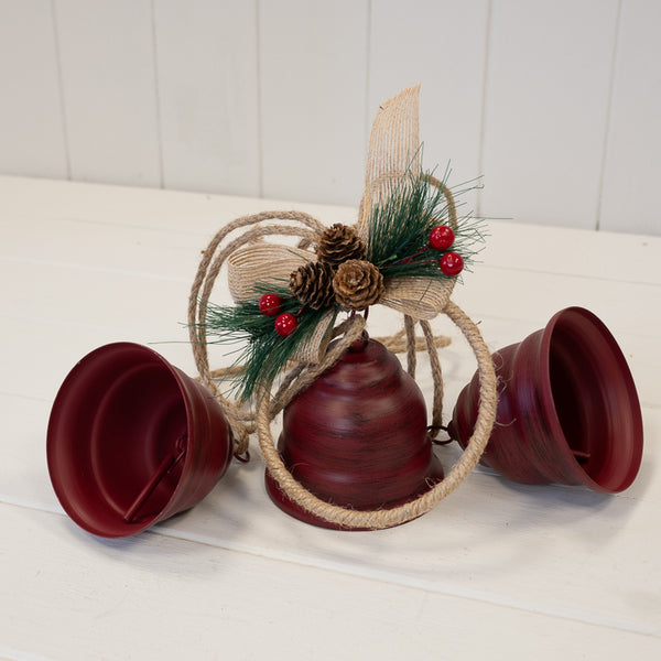Close-up of three red bells with hoop, ribbon and pinecone detail
